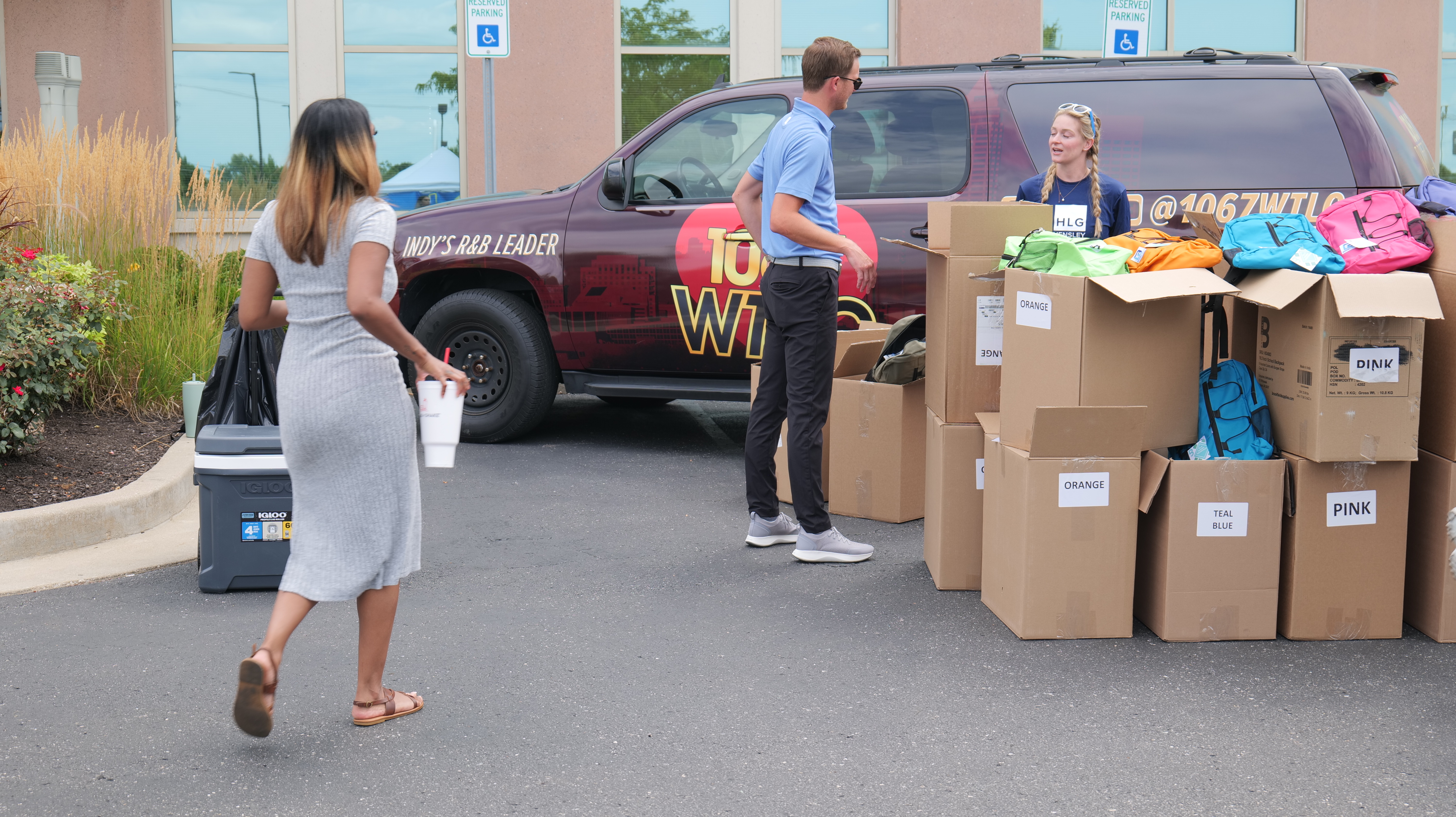 People loading boxes and bags into the back of a red truck with "INDY'S #1 RADIO LEADER" branding.